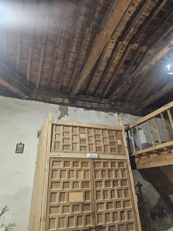 Puerta artesanal y coro de madera con escalera